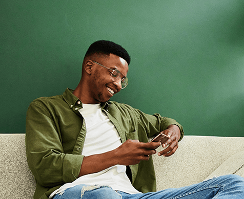 man relaxing on couch with mobile device